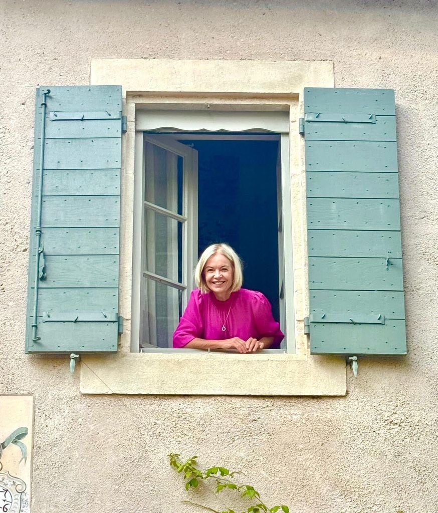 Mariella Frostrup leaning out of a window in a magenta shirt