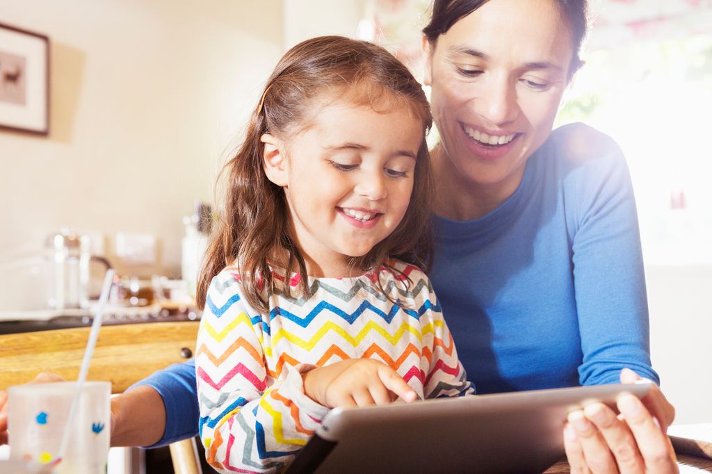 mother shows young child to use digital tablet