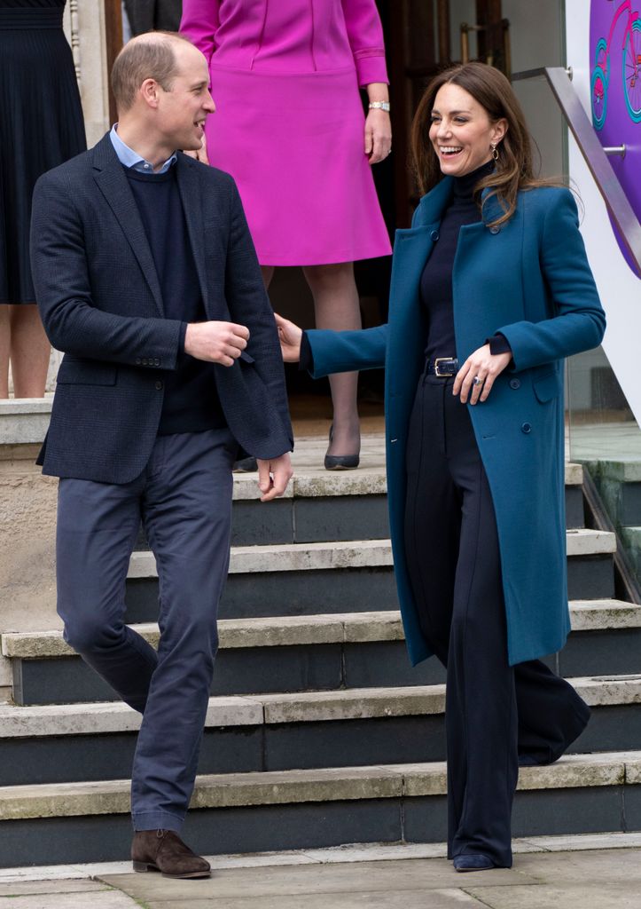 Princess Kate in a blue coat holding her husband Prince William's arm