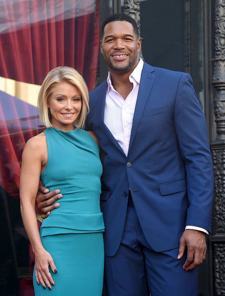 Kelly Ripa wearing a bright blue dress and Michael Strahan in a navy suit