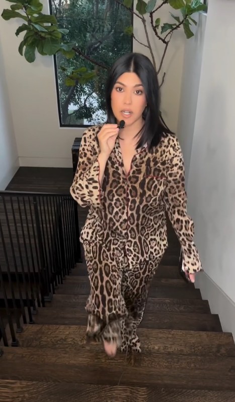 Kourtney Kardashian in leopard print outfit walking up stairs in her home