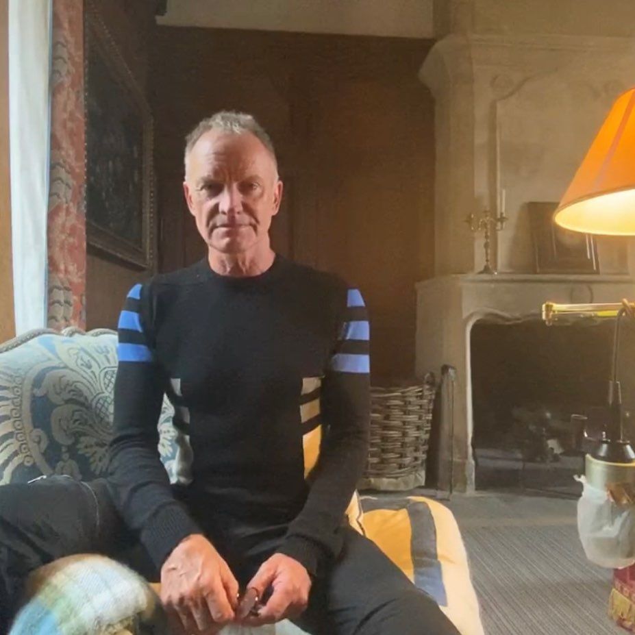 sting sitting on sofa at home in black top 
