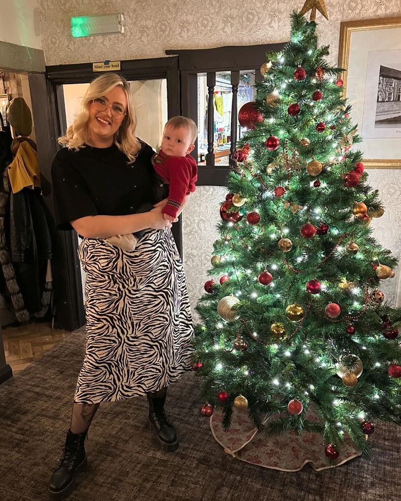 mother holding son in front of xmas tree 