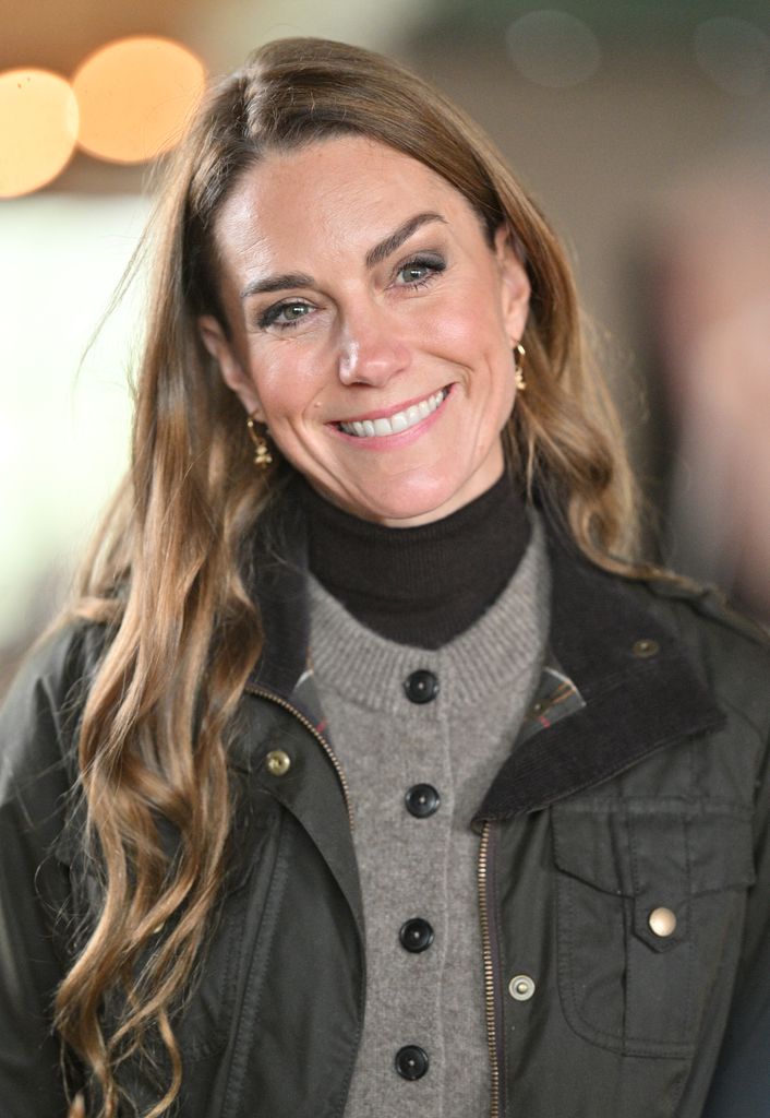 Catherine, Princess of Wales smiling in khaki waxed jacket and grey cardigan