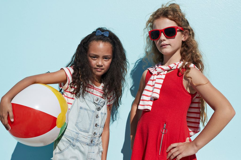 Portrait cool girls together on blue backdrop in summer
