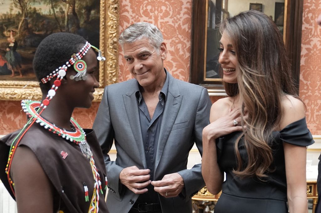 Amal and George Clooney speaking to person at buckingham palace