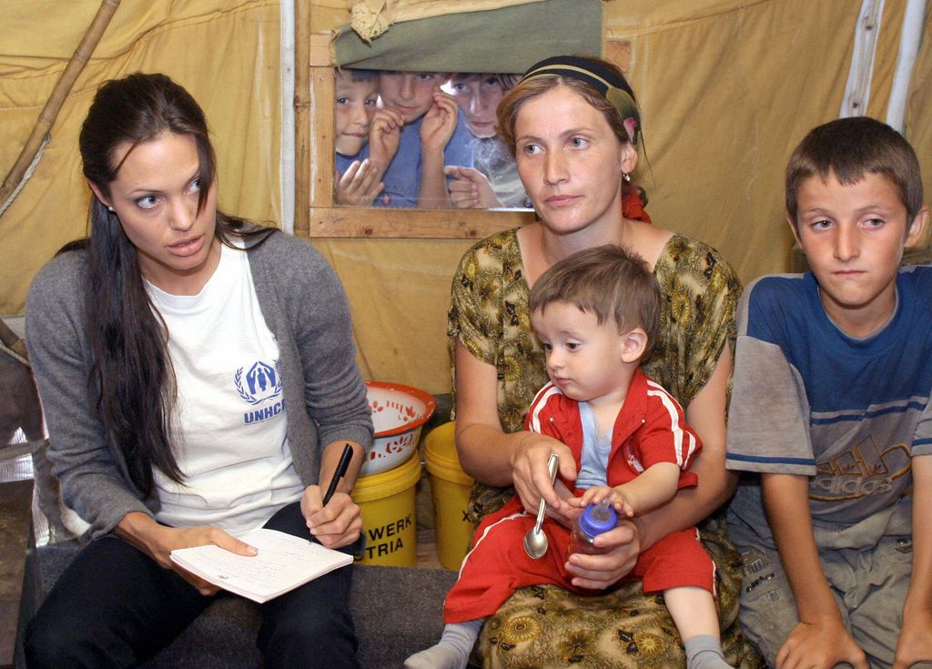 US screen actress Angelina Jolie, a goodwill ambassador for the UNHCR High Commissioner for Refugees (C) talks to refugees in a tent in 'Bella' refugee camp