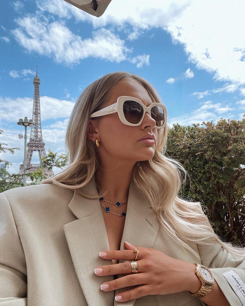Influencer Molly Mae in front of eiffel tower in beige blazer