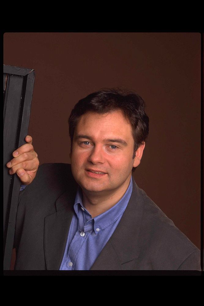 Eamonn Holmes wearing a black suit and blue shirt 