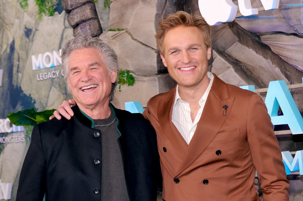 photo de Wyatt Russell avec une barbe de trois jours et des cheveux plus courts avec un bras autour de Kurt Russell