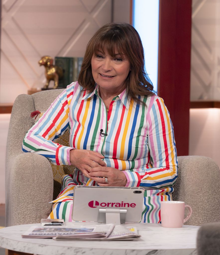 Lorraine Kelly wears multi coloured striped dress while sitting on armchair to present her ITV show