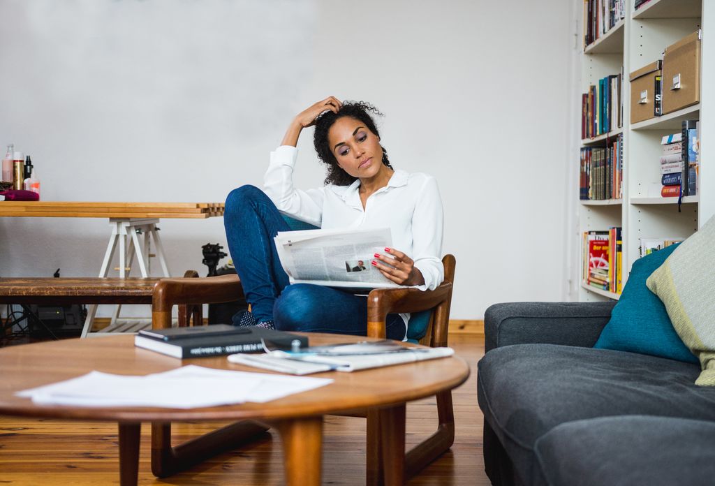 Woman thinking and reading the newspaper in the living room