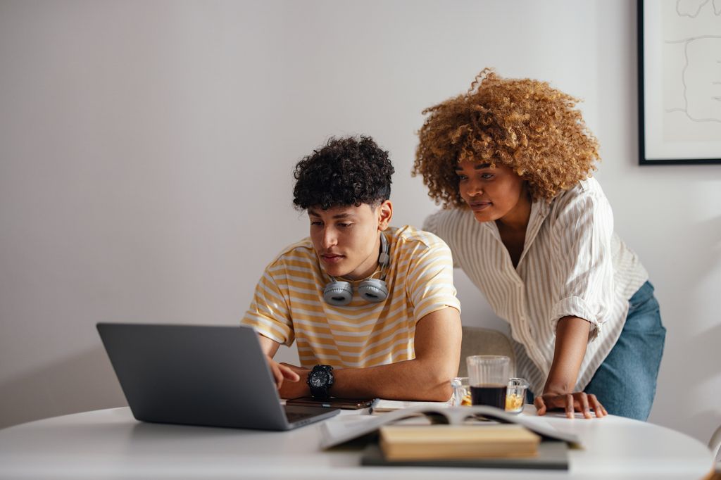 mother and her teenage son focusing on a laptop at home