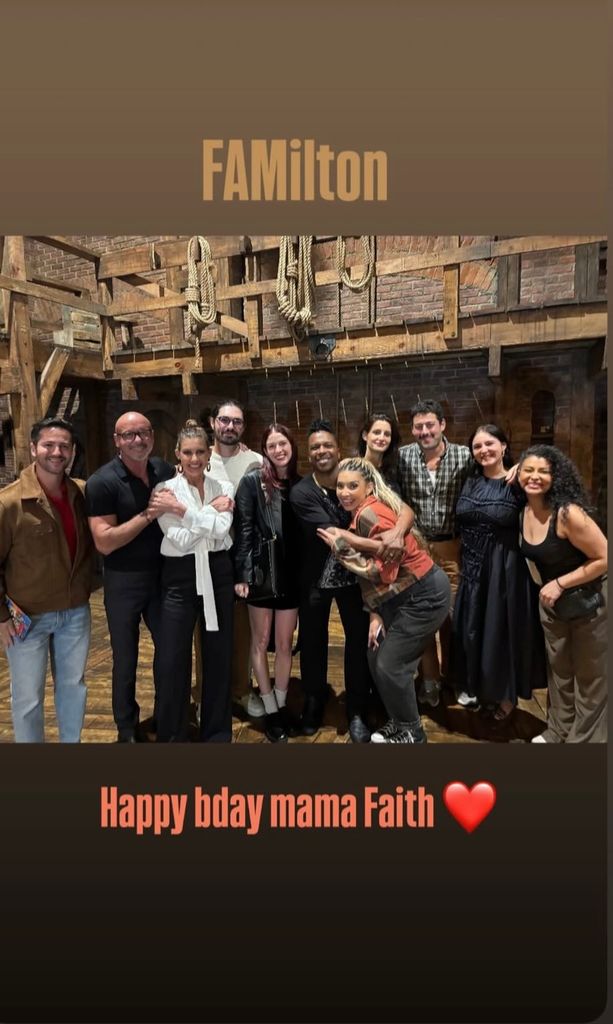 Tim with bald head hugging Faith with his daughters and some of the cast of Hamilton on set