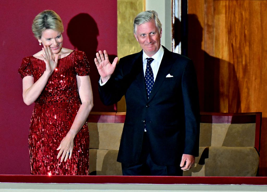 Queen Mathilde waving in a red sparkly dress