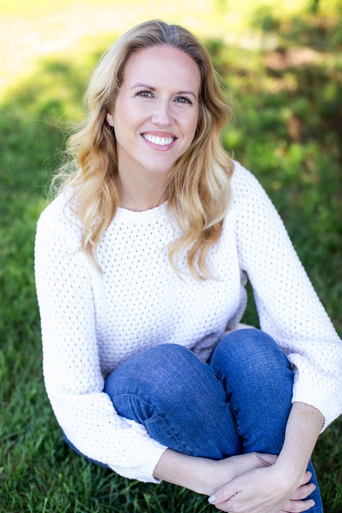 blonde woman in a jumper sitting on grass