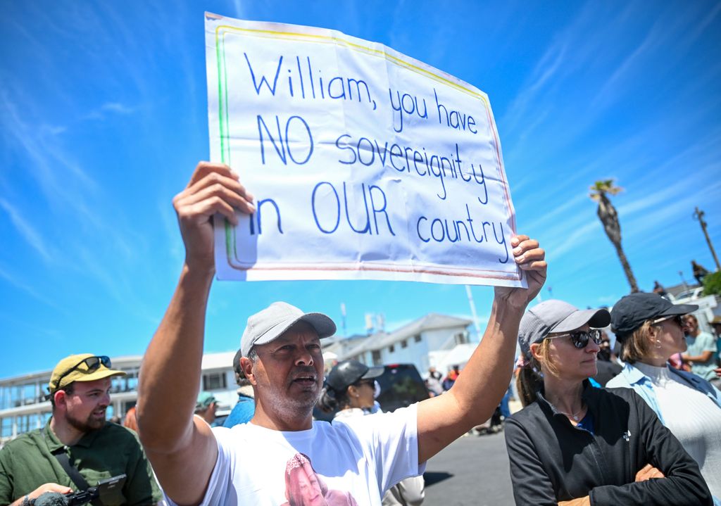 A protestor holding a sign that reads 'William, you have no sovereignity in our country'