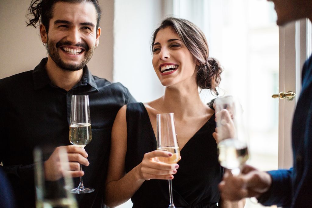 Happy man and woman holding champagne flutes during dinner party at home