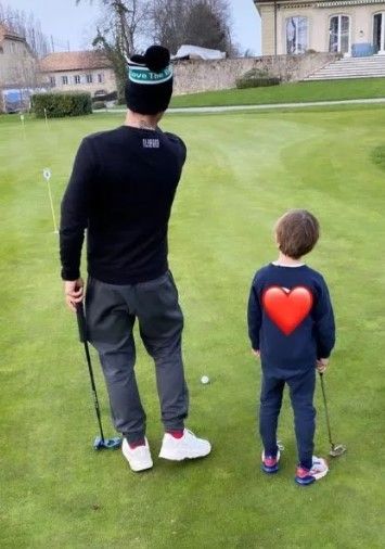Robbie Williams wearing bobble hat playing golf with lookalike son Charlie 
