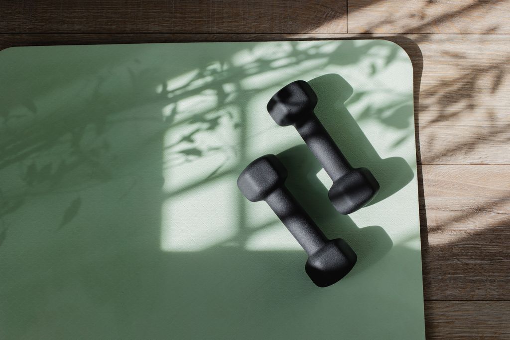 Tapis de yoga et haltères au sol avec la lumière du soleil de l'ombre. 