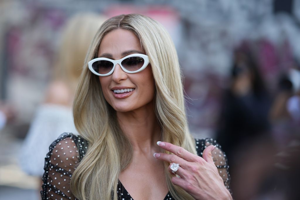 Paris Hilton in a black dress, sunglasses and a giant diamond ring