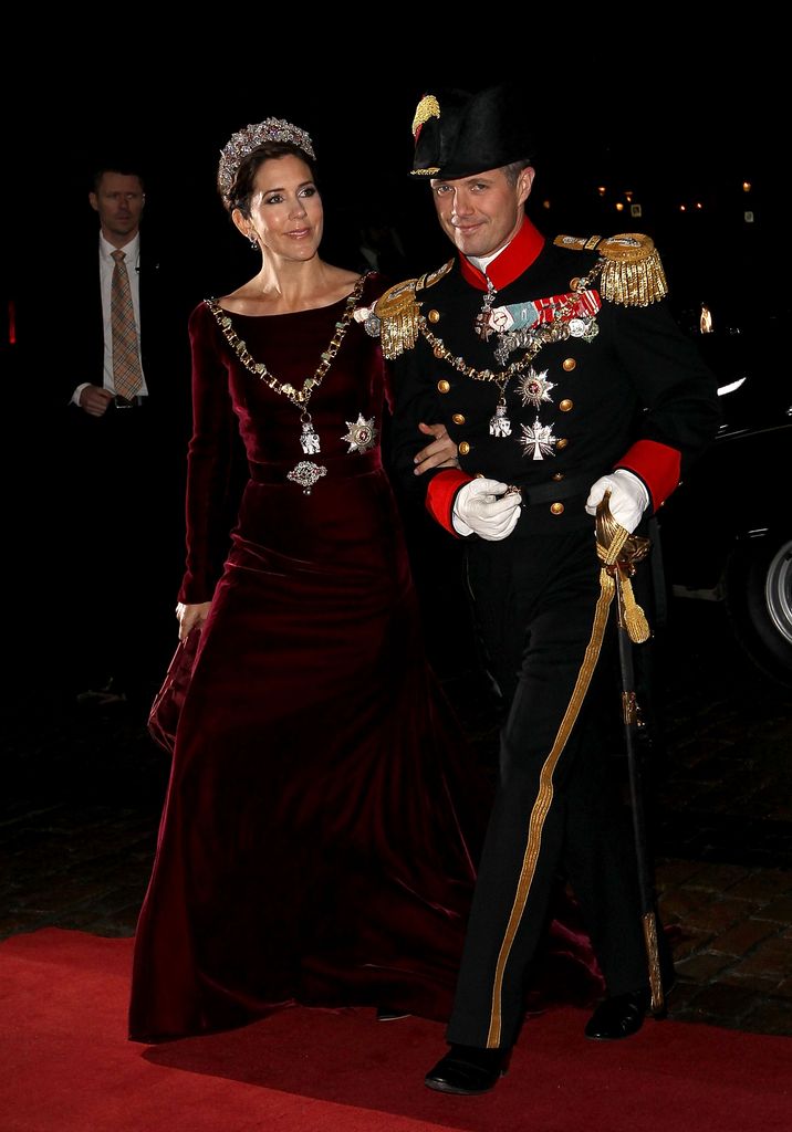 Crown Princess Mary in burgundy dress holding arm of frederik