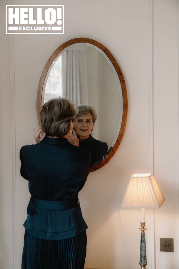 A woman putting earrings on whilst looking at the mirror