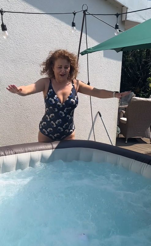 Nadia Sawalha on side of cold pool in floral swimsuit