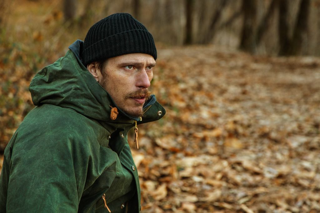 close-up of man in coat in leafy woodland