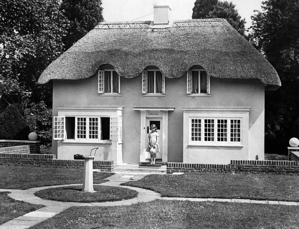 Elizabeth II is standing in front of a model house, which was built in the style of an old Welsh country house