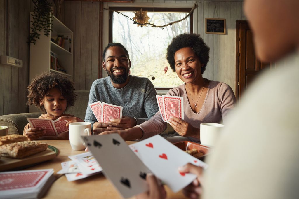 Happy family enjoying while playing cards in the living room.