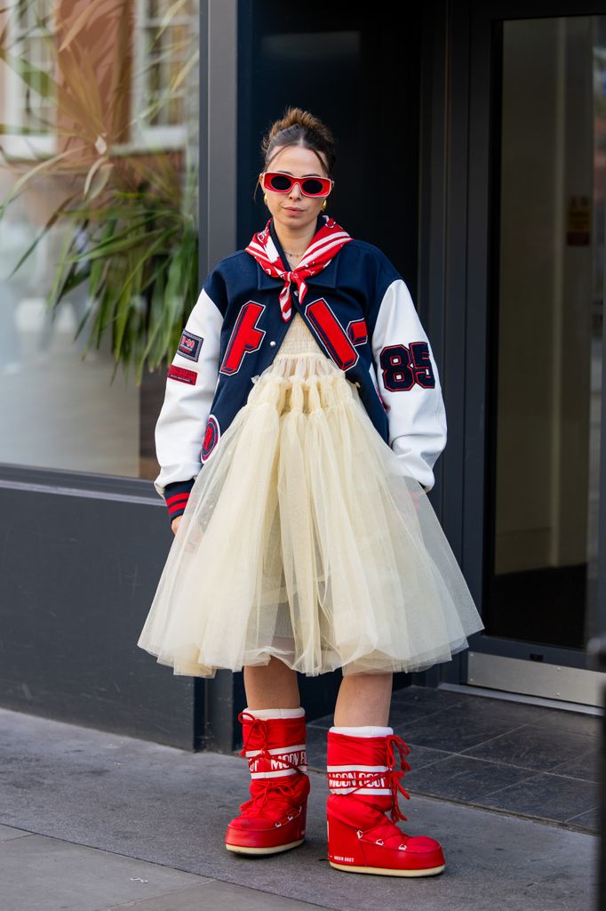 H! Fashion's Orion Scott wearing red Moon Boots, a yelloe Molly Goddard tulle dress and a baseball jacket, teamed with red sunglasses