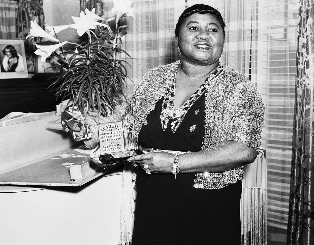American actress Hattie McDaniel (1895 - 1952) with her Academy Award of Merit for Outstanding Achievement, circa 1945. McDaniel won an Oscar for Best Supporting Actress for her role of Mammy in 'Gone With The Wind', making her the first African-American to win an Academy Award. (Photo via John Kobal Foundation/Getty Images)