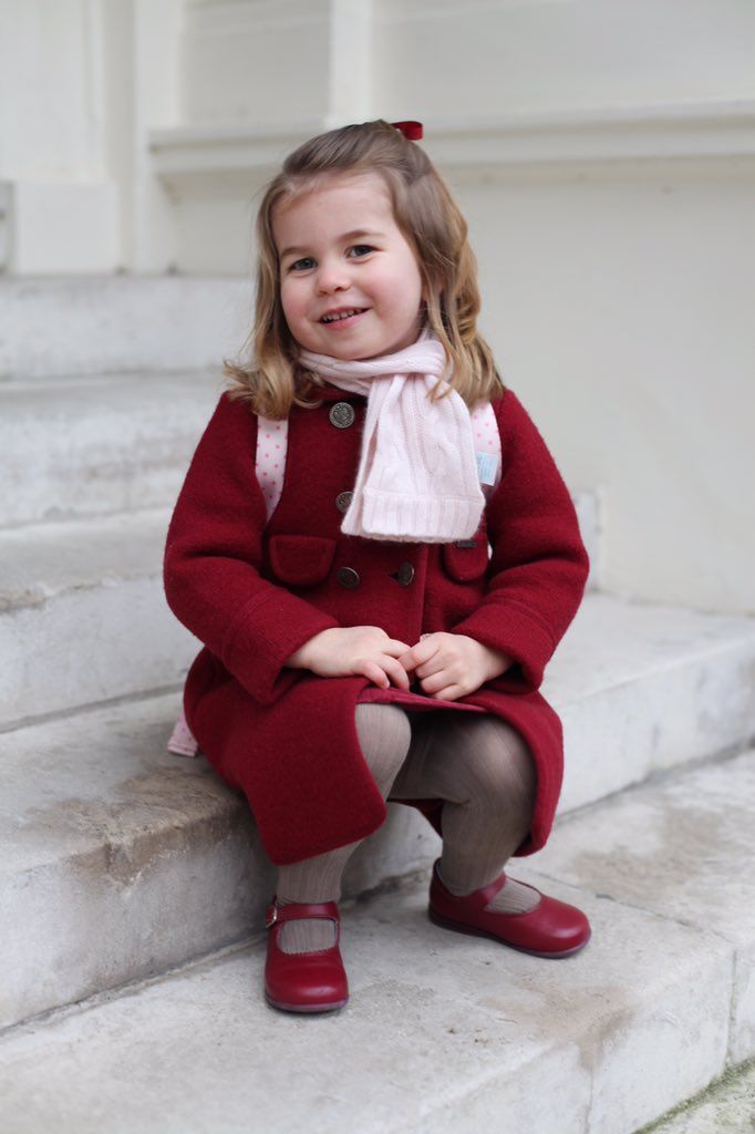 Princess Charlotte in a red coat sitting on steps on her first day at nursery in 2018