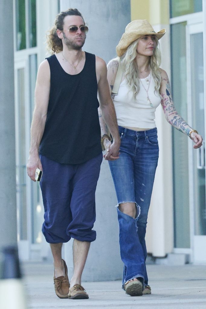 Paris wears a sheer vest and flared jeans