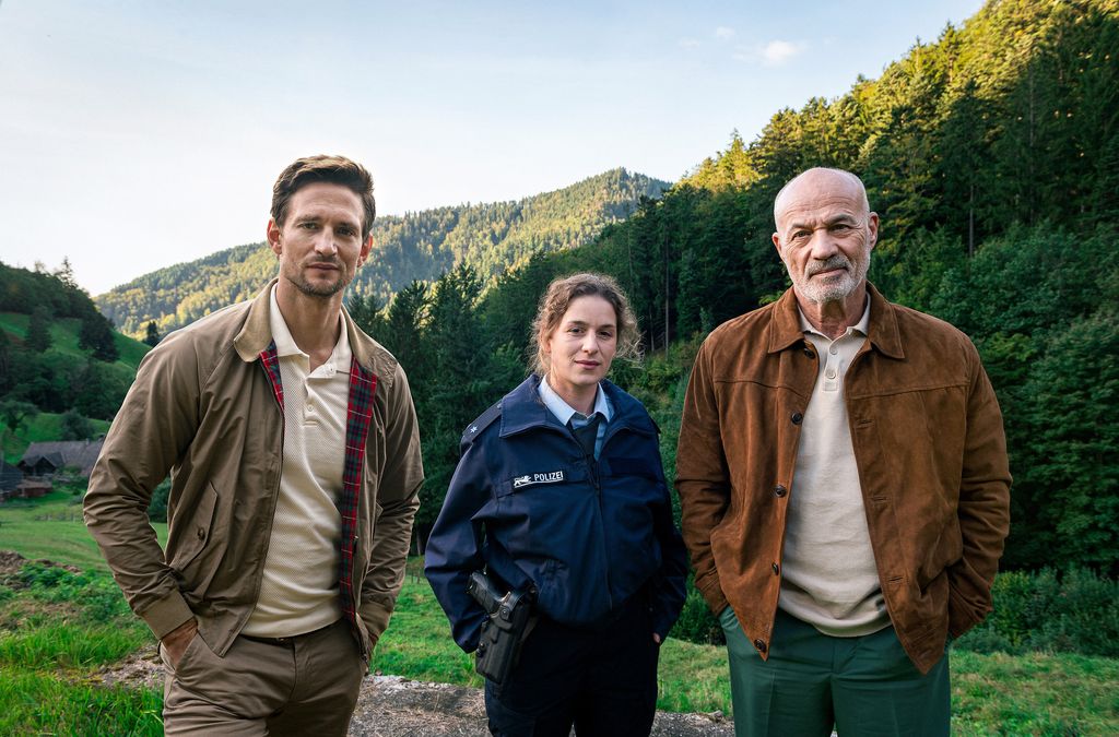 three people standing in front of mountains