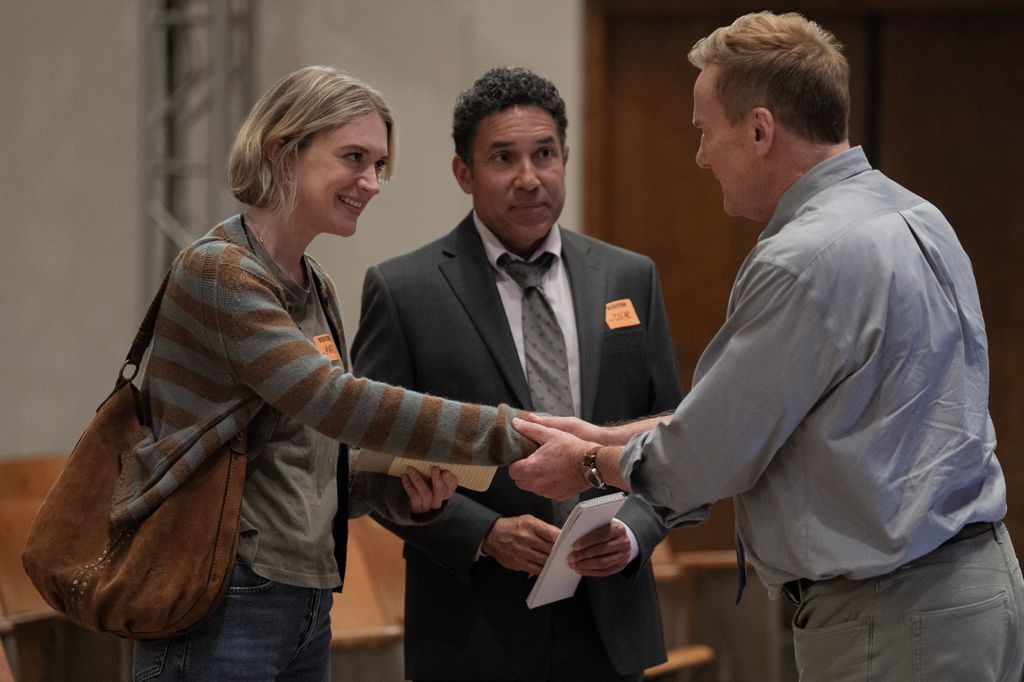 woman and man shaking hands next to man