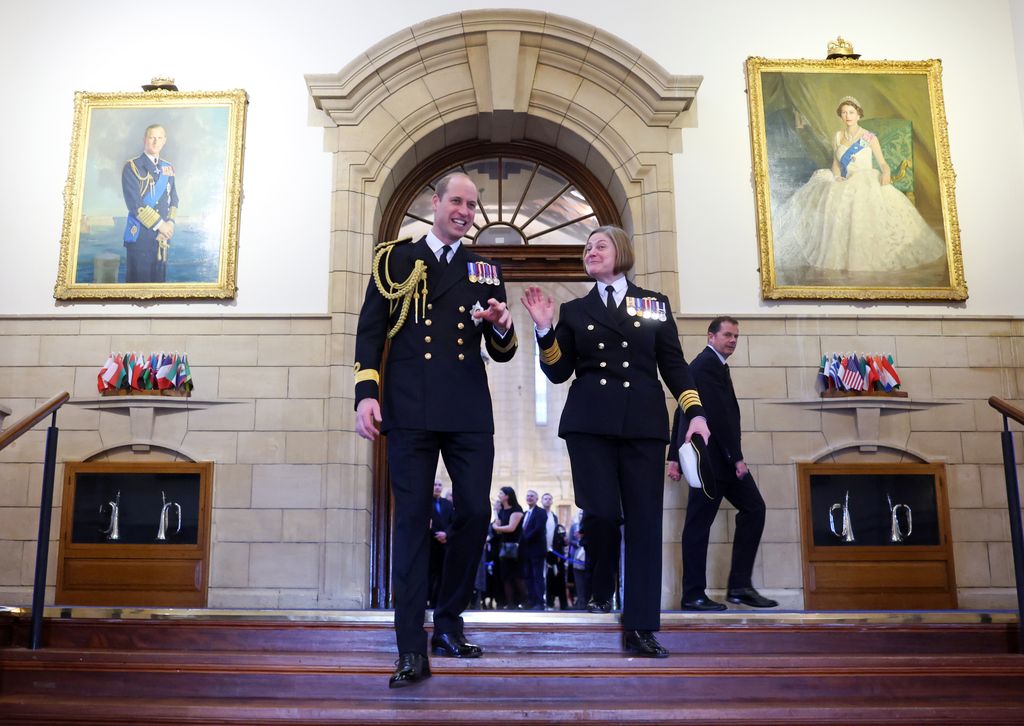 Prince William at Dartmouth naval college in front of a portrait of the late Queen and Prince Philip