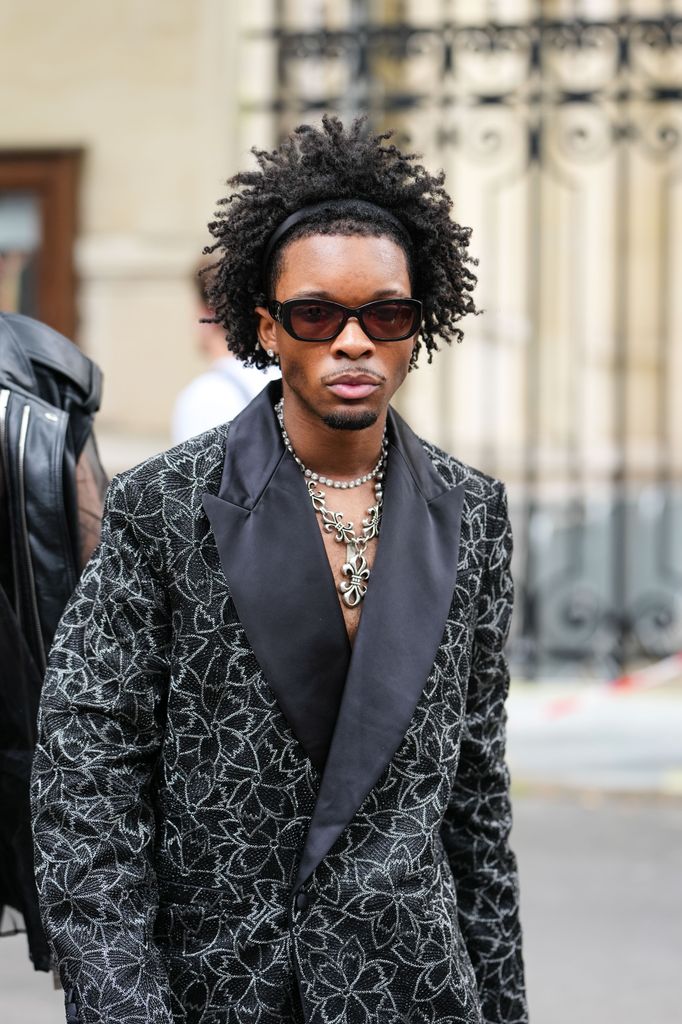 d4vd wears black Chanel sunglasses, diamond stud earrings, white gold diamond choker, silver Chrome hearts necklace, black silver floral beaded oversized Amiri blazer jacket, outside Amiri, during the Paris Fashion week Men's Spring/Summer 2026 on June 26, 2025 in Paris, Franco