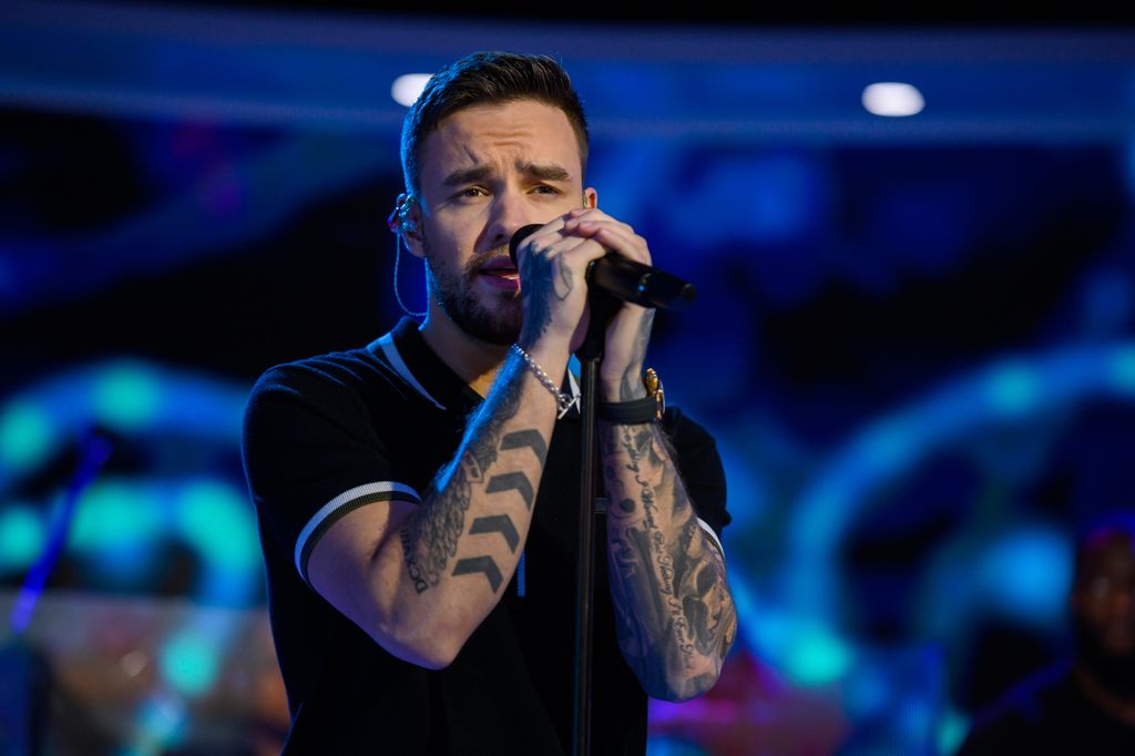 Liam Payne in a black T-shirt sings into the microphone