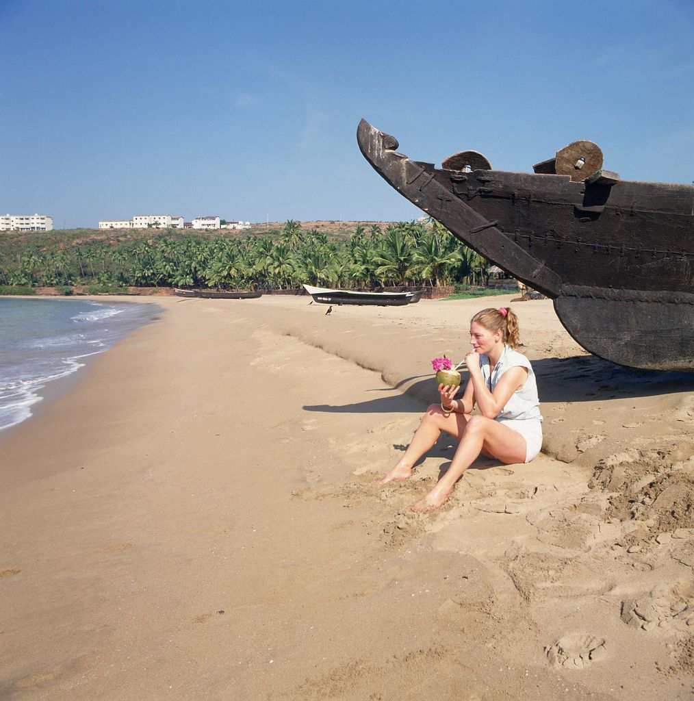 Geraldine James est assise sur la plage en sirotant une noix de coco.