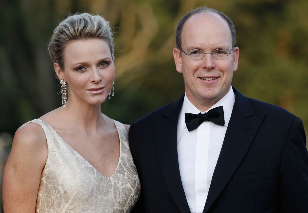 Princess Charlene of Monaco in a cream dress with drop earrings next to husband Prince Albert II 