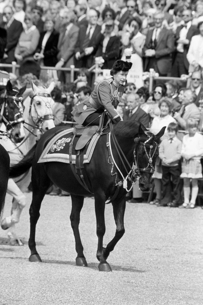 Queen Elizabeth II leans forward to reassure her horse after a man fired a replica gun