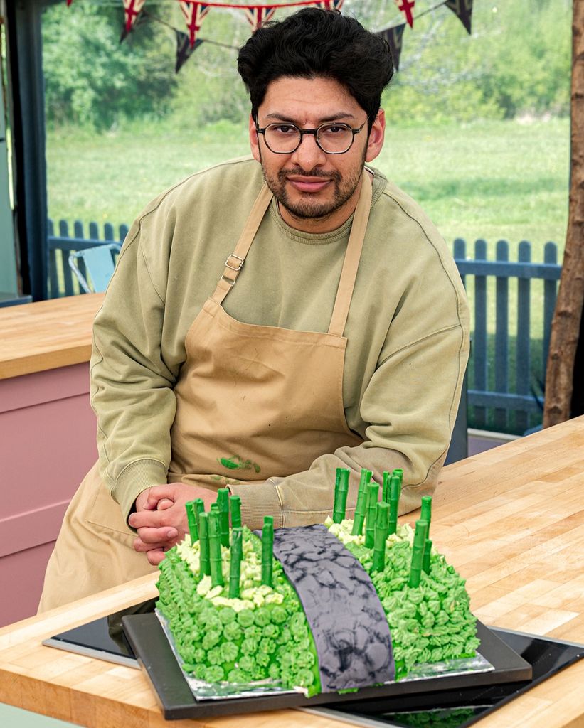 A man stands next to a green cake
