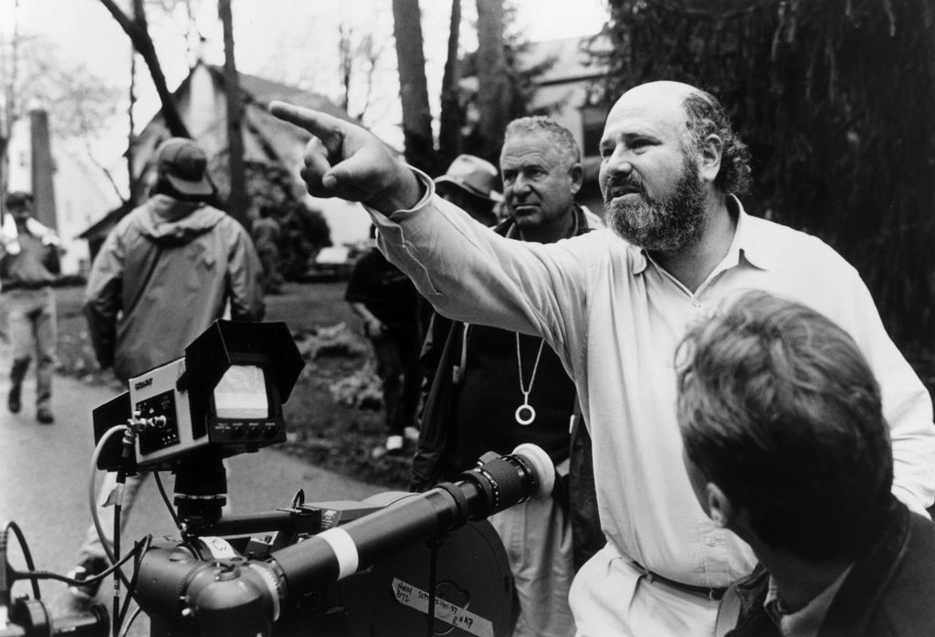 American director, producer, and actor Rob Reiner gestures near a camera while crew members surround him outdoors on the set of his film, 'North'