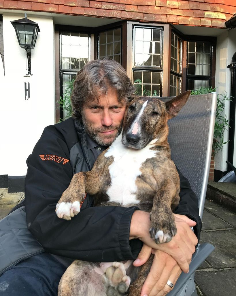 john bishop hugging pet dog outside 