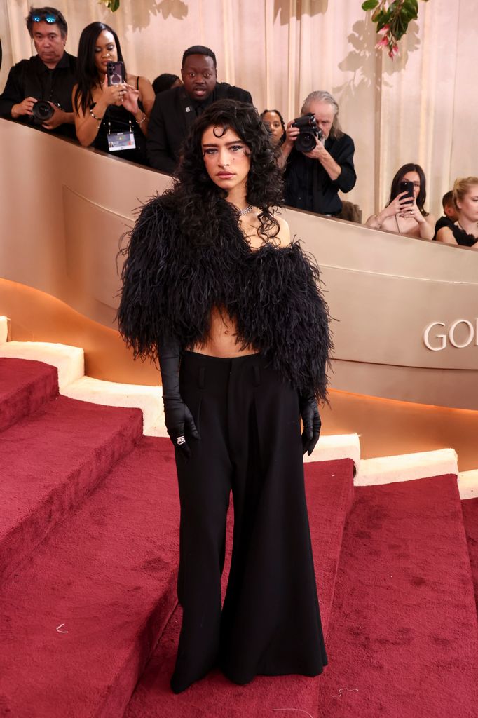 Odessa A'zion wearing a vintage Dolce & Gabbana oversized feathered top, black trousers and her hair loose and curly.
