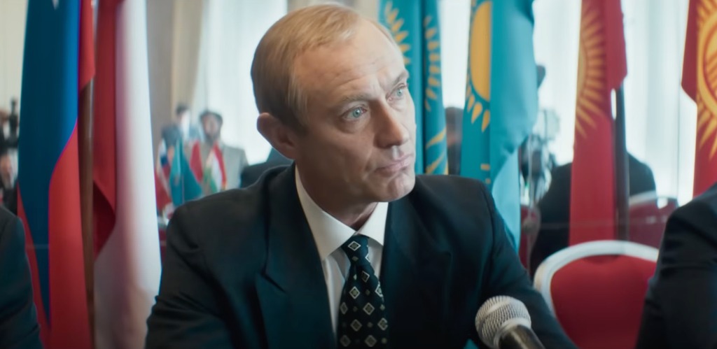 man in suit sitting behind microphone