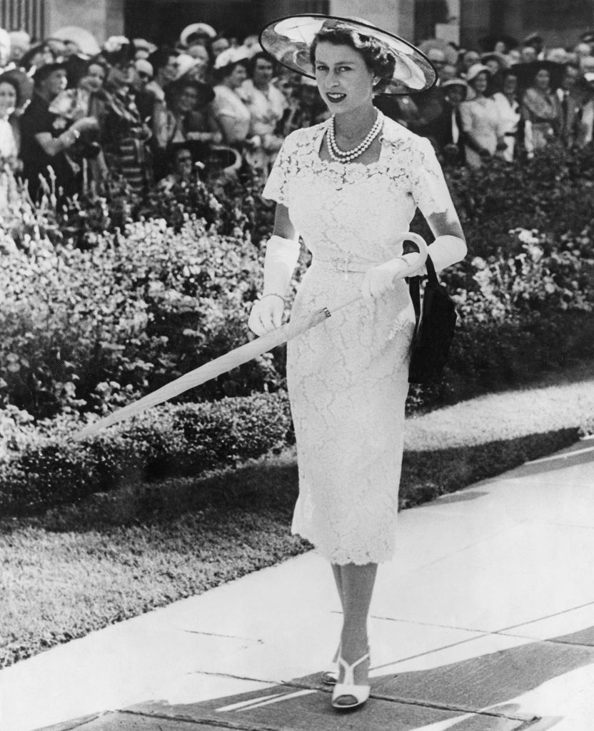 Queen Elizabeth II wears a slim-fitting white lace dress to a garden party in Sydney, Australia, before leaving for Tasmania on the liner 'SS Gothic', February 1954. Her hat is of black tulle with three feathers. (Photo by Keystone/Hulton Archive/Getty Images)