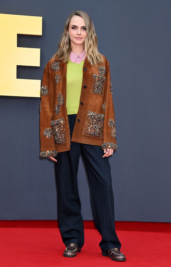 Cara Delevingne on red carpet in brown jacket